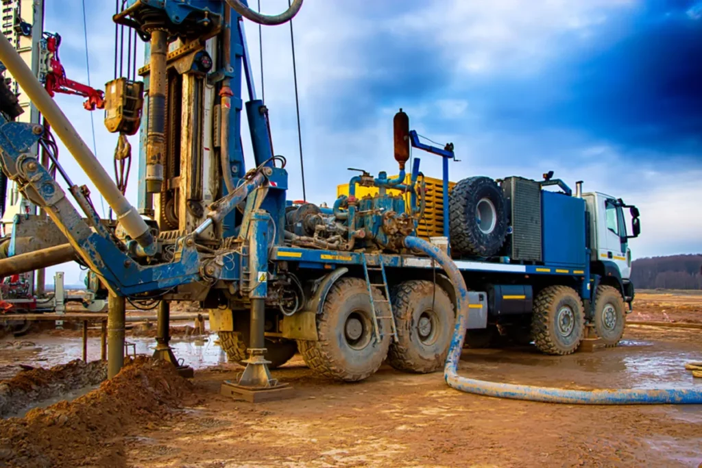 Water well rig enlarging a pilot hole with tricone bits